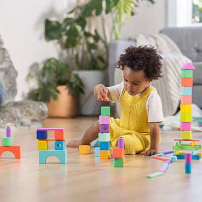 a child stacking vibrantly colored blocks of many shapes