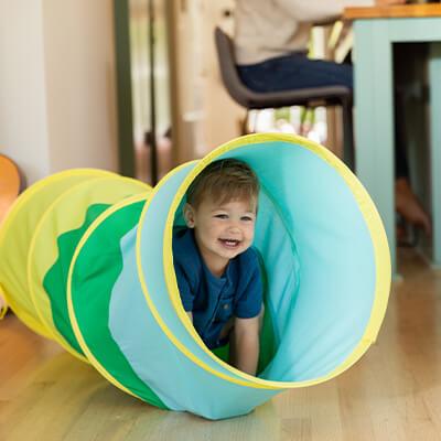 a child playing in a flexible, collapsible tunnel